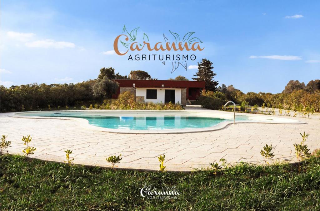 una piscina con una casa sullo sfondo di Agriturismo Caranna a Torre Lapillo