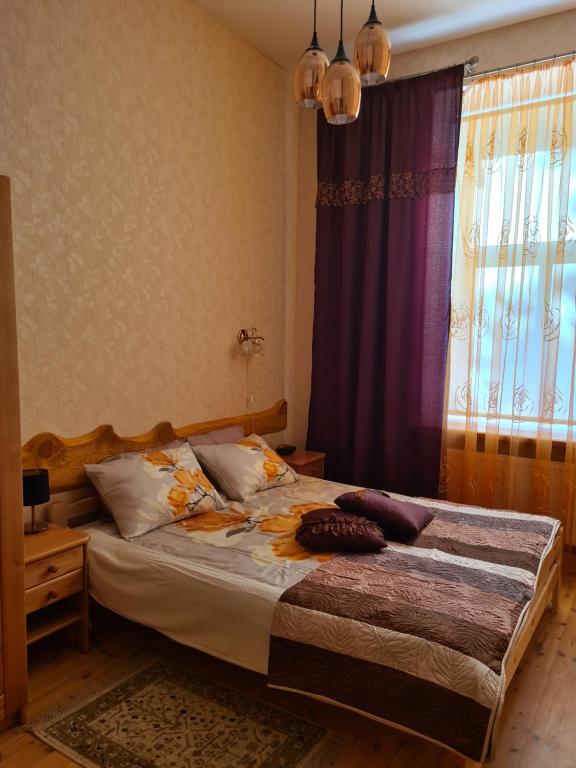 a bedroom with a bed and a window with purple curtains at Libau Baden apartamenti in Liepāja
