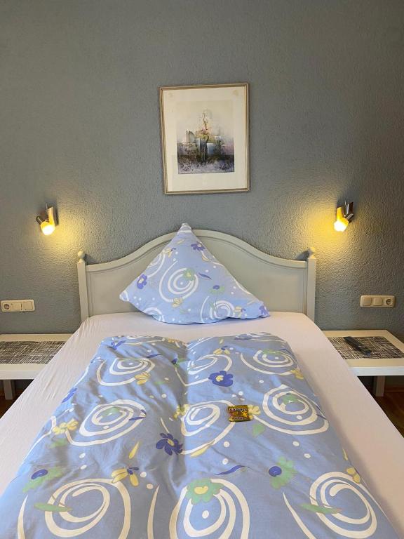 a bed with a blue comforter and two pillows at Hotel Weller in Riedstadt