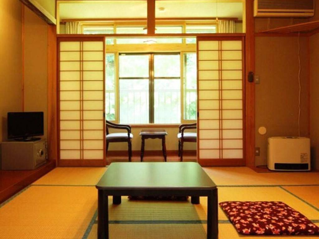 Zimmer mit einem Tisch, Stühlen und einem Fenster in der Unterkunft Oyado Fubuki - Vacation STAY 45512v in Nozawa Onsen