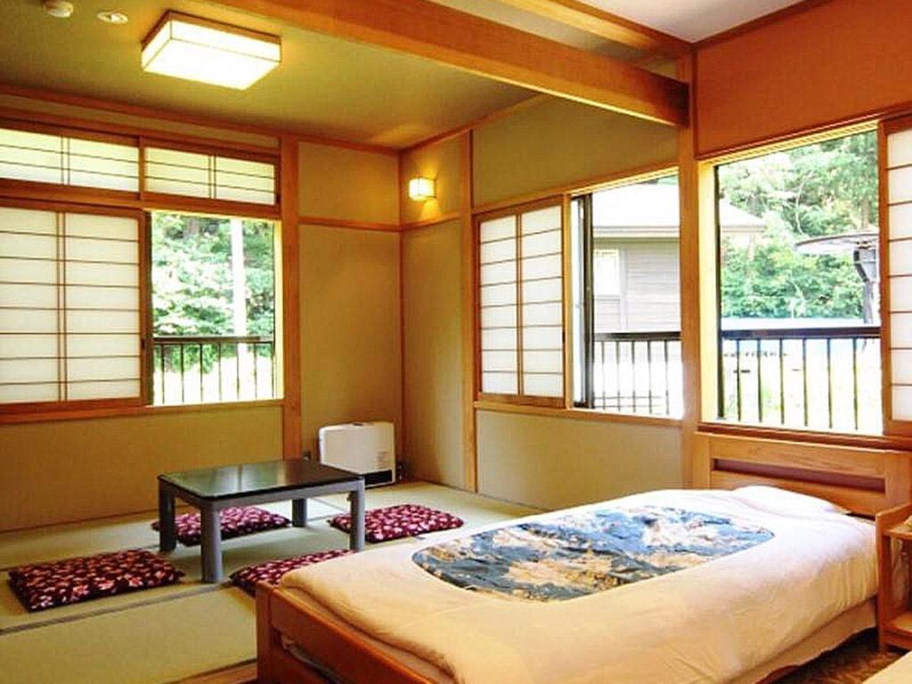 1 dormitorio con cama, mesa y ventanas en Oyado Fubuki - Vacation STAY 45516v, en Nozawa Onsen