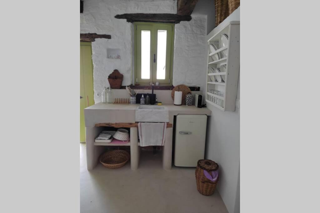a white kitchen with a sink and a window at Το Παράσπιτο in Skiros