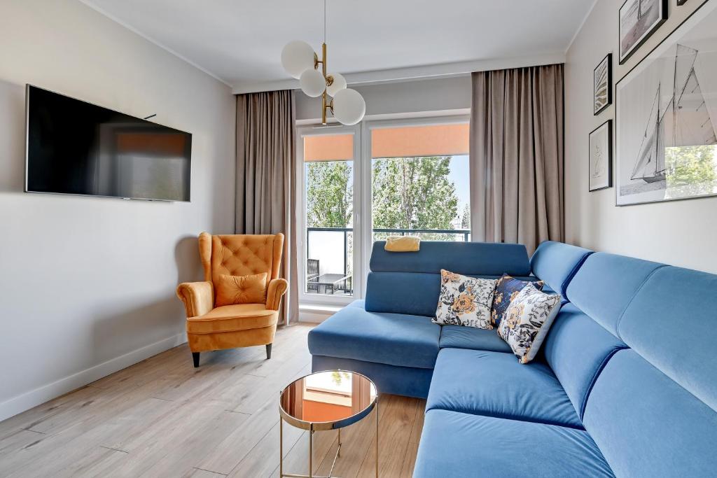 a living room with a blue couch and a chair at Wave Apartments - Mezzo in Gdańsk
