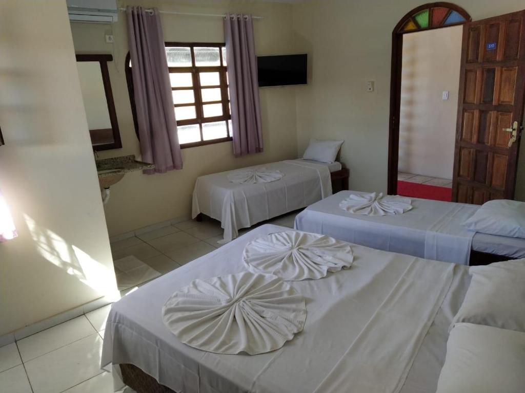 um quarto com três camas e uma janela em Hotel Sol Bahia em Porto Seguro