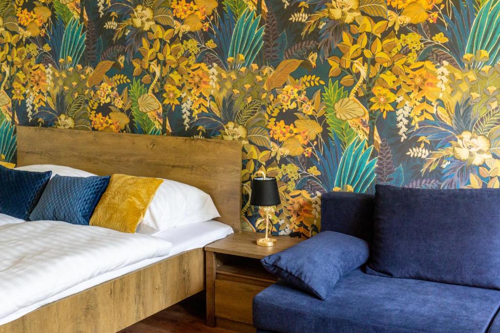 - une chambre avec un lit, une chaise et du papier peint dans l'établissement Secret Garden Apartman, à Miskolc