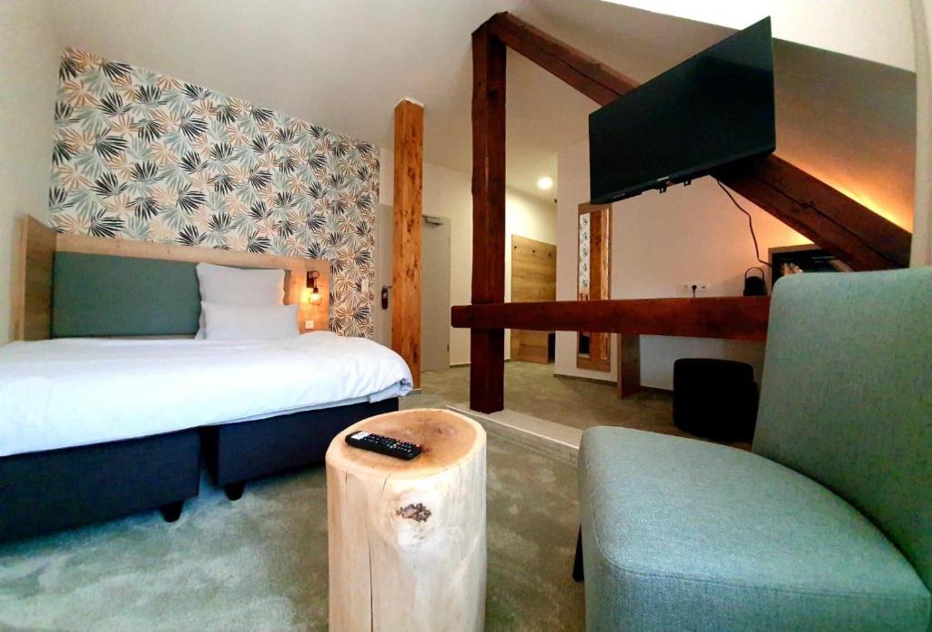 ein Schlafzimmer mit einem Bett, einem TV und einem Sofa in der Unterkunft Hotel Le Filou in Hille