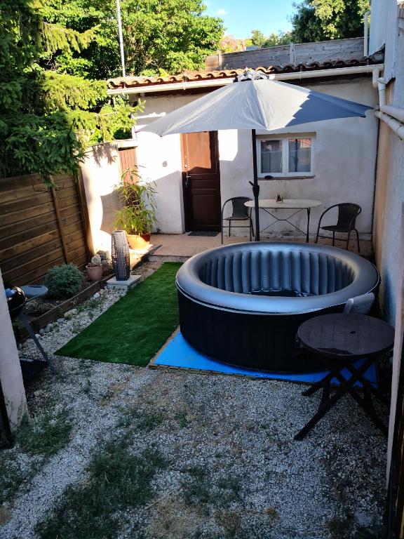 une cour avec une grande piscine gonflable et un parasol dans l'établissement LE STUDIO REMCAM, à Saint-Mitre-les-Remparts