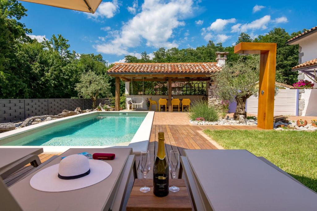 een zwembad met een tafel en een fles wijn bij Oasis Natura - Villa Antonio in Jurdani
