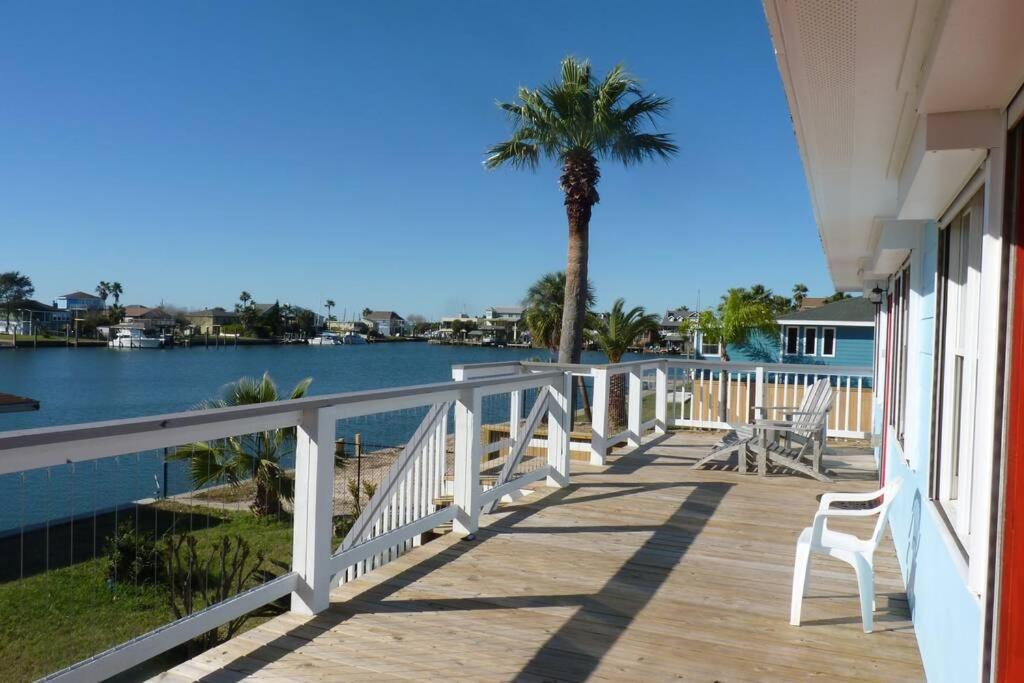 eine Veranda mit Stühlen, einer Palme und Wasser in der Unterkunft Paradise lagoon*bayhouse fishing*beach*Dogfriendly in Galveston