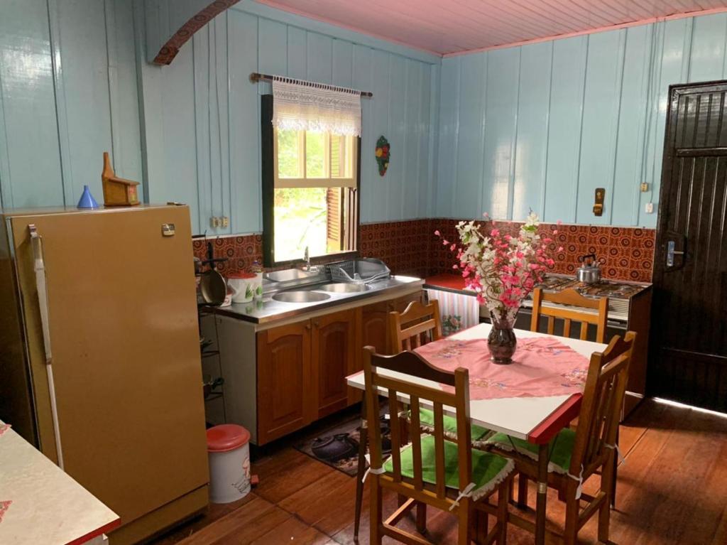 a kitchen with a table with a vase of flowers on it at CASA TREIN - há 20 minutos do centro de Gramado in Três Coroas