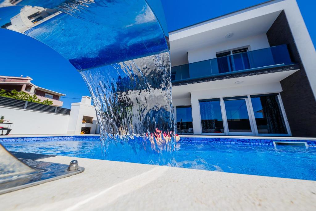 - une piscine avec une fontaine en face d'une maison dans l'établissement Vila Morena, à Kaštela