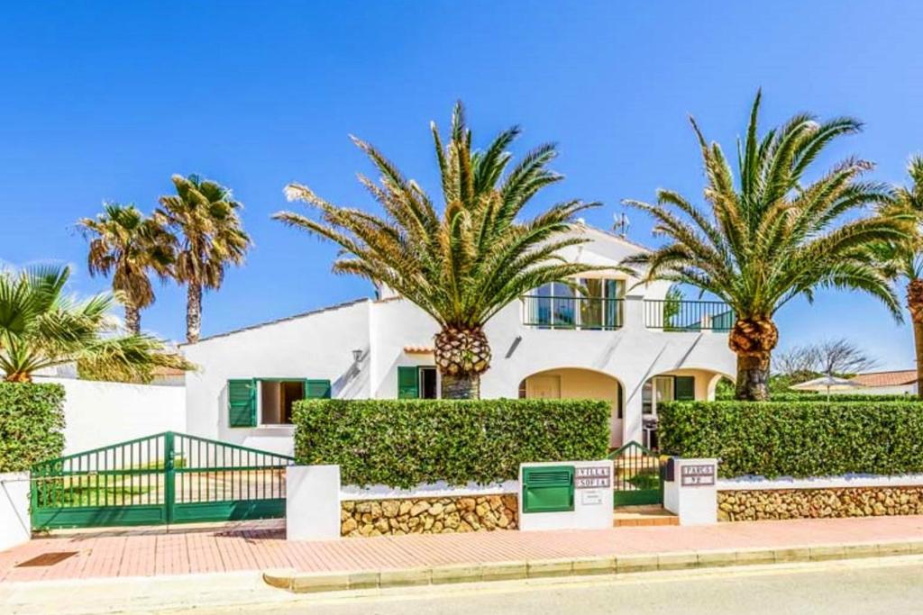 a white house with palm trees in front of it at Villa SOFIA in Cala en Forcat