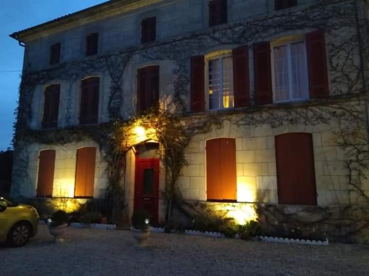 Rouffignac的住宿－Chambre confortable dans maison bourgeoise，一座房子,前面有一扇红色的门和一辆汽车