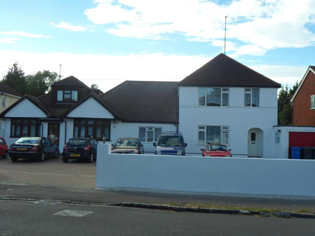 una casa blanca con coches aparcados en un estacionamiento en London Heathrow Guesthouse, en Hillingdon