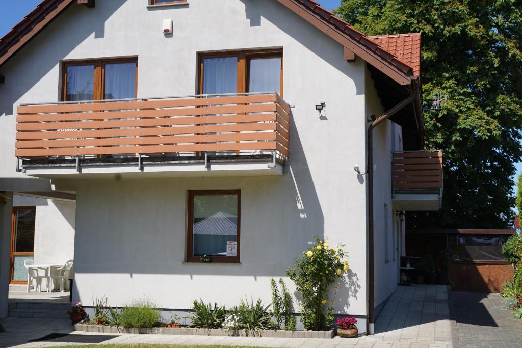 a white house with a wooden balcony at Dom Wypoczynkowy IRMINA in Karwia