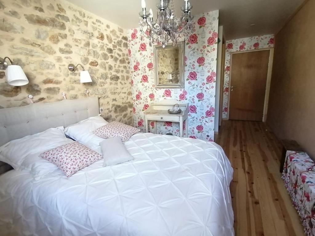 a bedroom with a large white bed with pink pillows at Achilée Les Herbes de la saint Jean in Saint-Bonnet-le-Froid