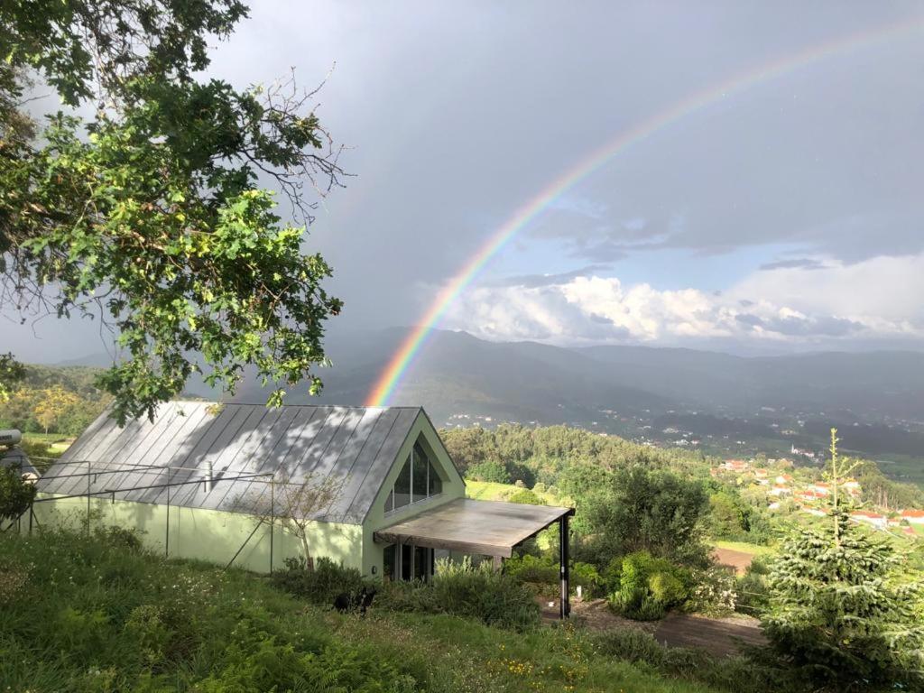 ein Regenbogen über einem grünen Gebäude mit einem Haus in der Unterkunft Casa do Eido dos Calhões in Ponte de Lima