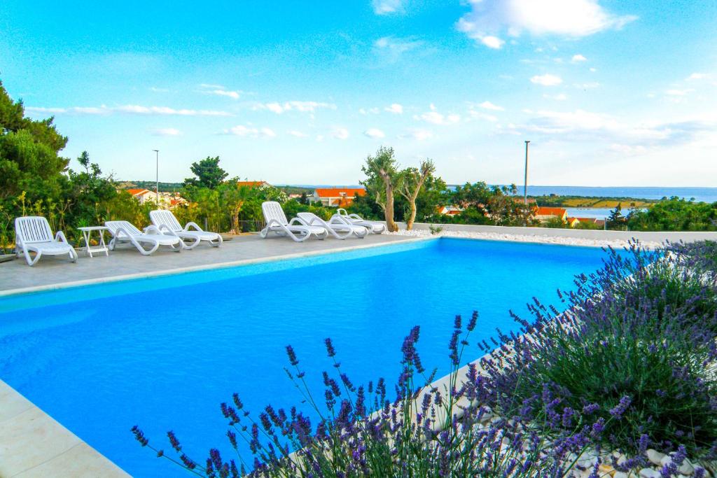 einen Pool mit Stühlen und Meerblick in der Unterkunft Villa Apartments AniFil in Novalja