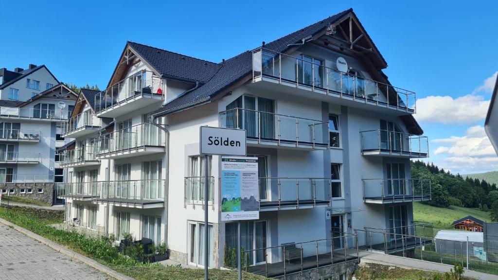 ein weißes Wohnhaus mit einem Schild davor in der Unterkunft Apartament Czarna Góra S26 in Heudorf
