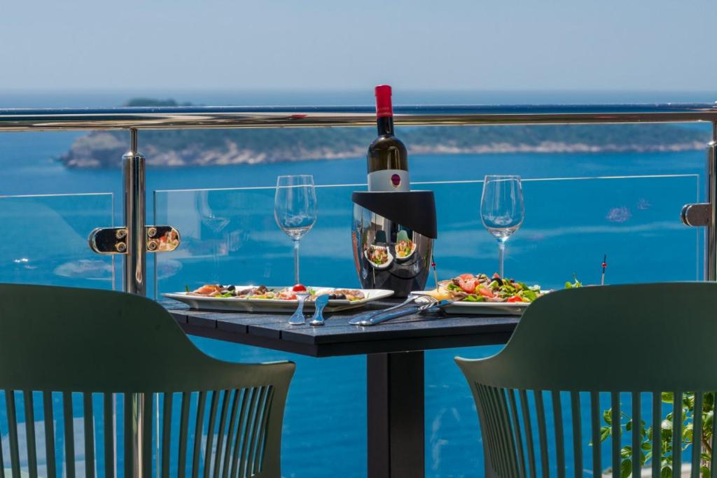 un tavolo con due piatti di bicchieri da cibo e da vino di Deluxe Cosmopolit apartment a Cavtat