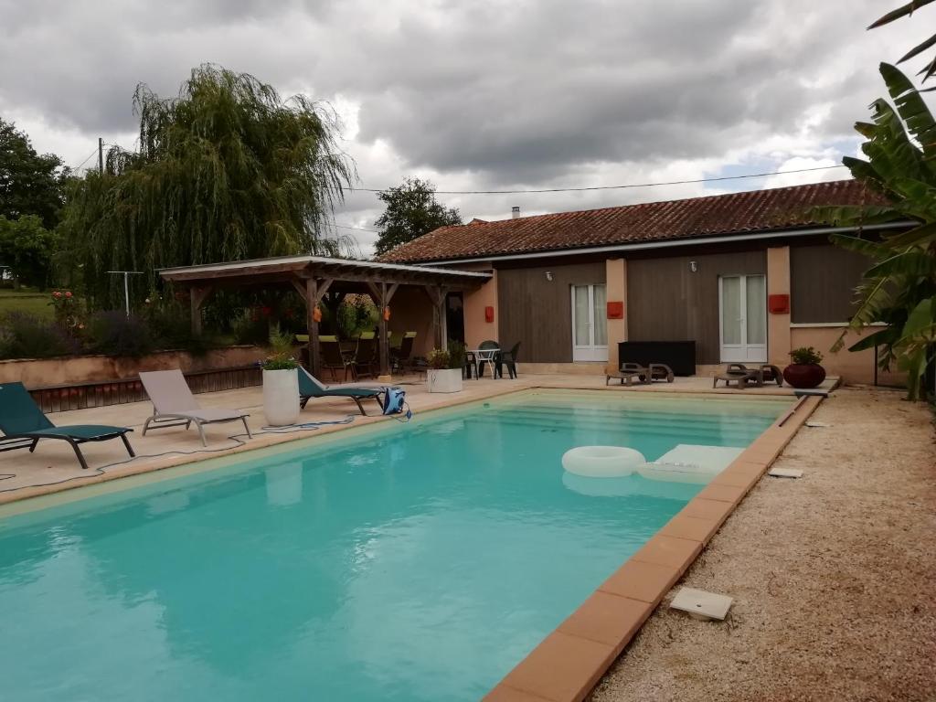 une grande piscine avec des chaises et une maison dans l'établissement La Maison de Joindy, à Saint-Cyprien