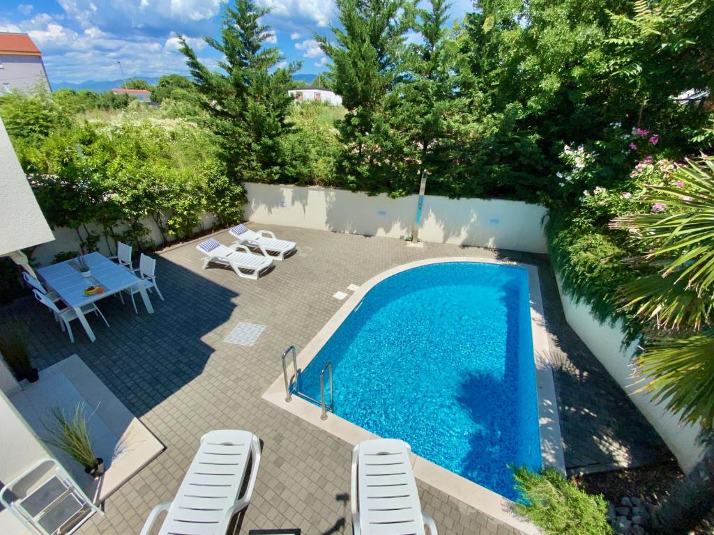 an overhead view of a swimming pool with chairs and trees at Private pool and Mediterranean garden apt Mia in Šilo