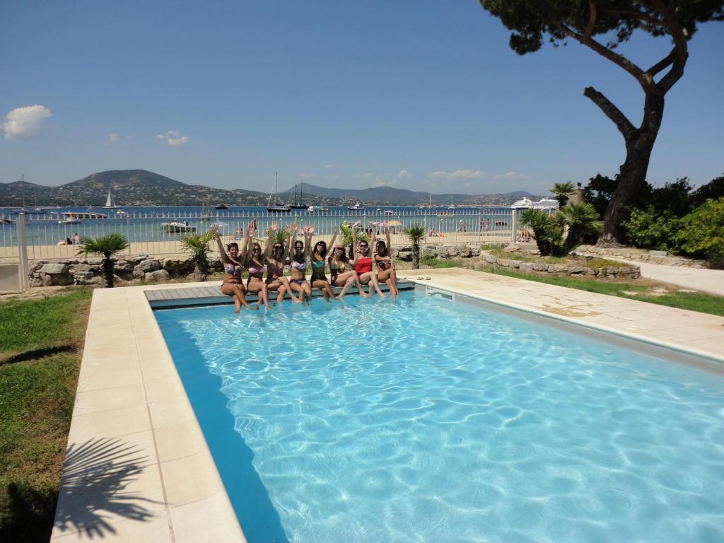 a group of people sitting on the edge of a swimming pool at Villa Playa del Sol -B4 in Saint-Tropez