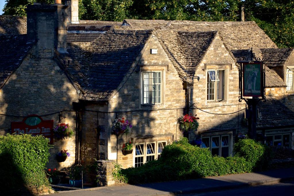 an old stone house with flowers in the window at The Lamb Inn in Bourton on the Water