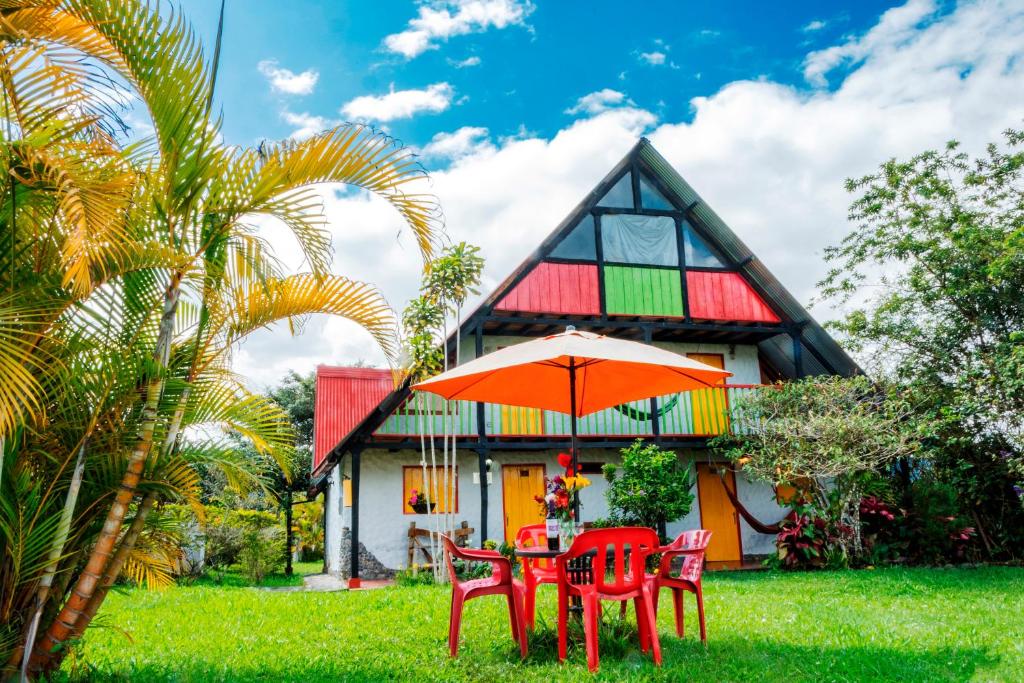 a table with chairs and an umbrella in front of a house at Hotel Alto de los Andaquies in San Agustín