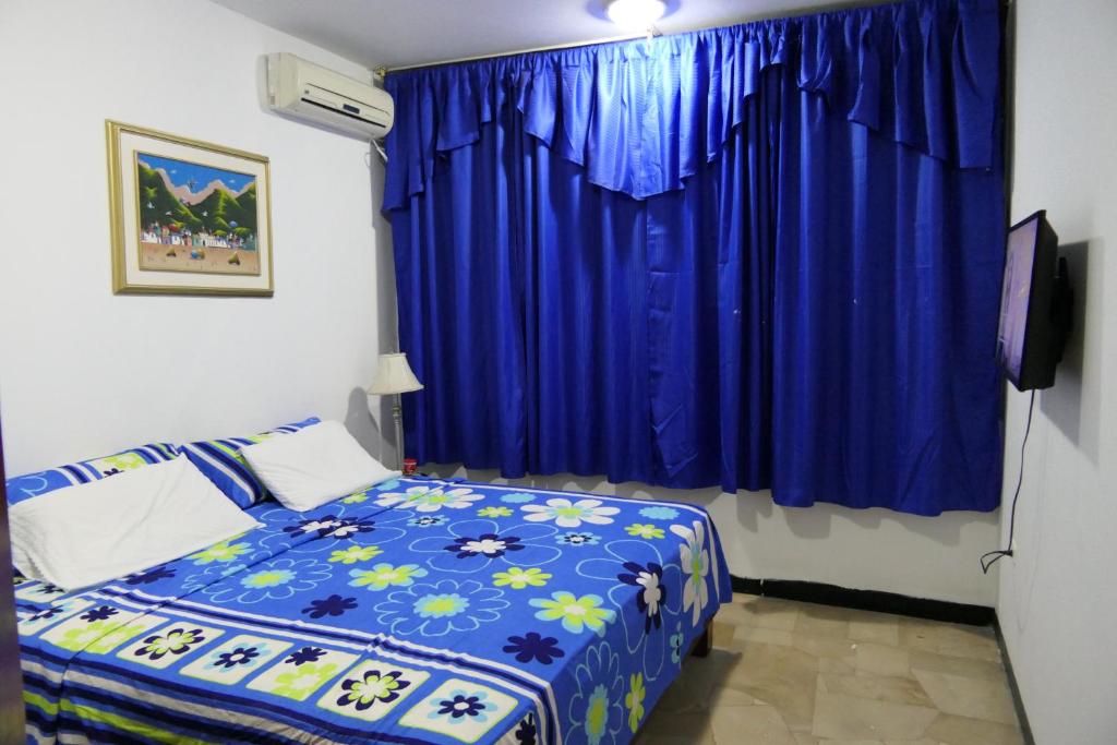 1 dormitorio con cama y cortina azul en Departamentos 3 hab Manta - centro, en Manta