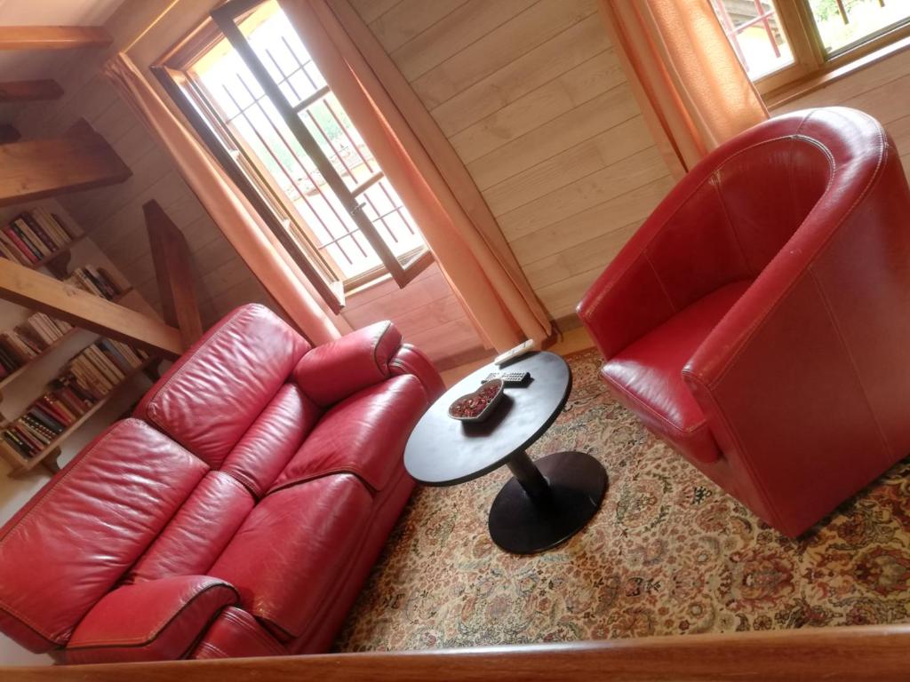 a living room with a red leather couch and a table at "Côté plage" in Aubeterre-sur-Dronne