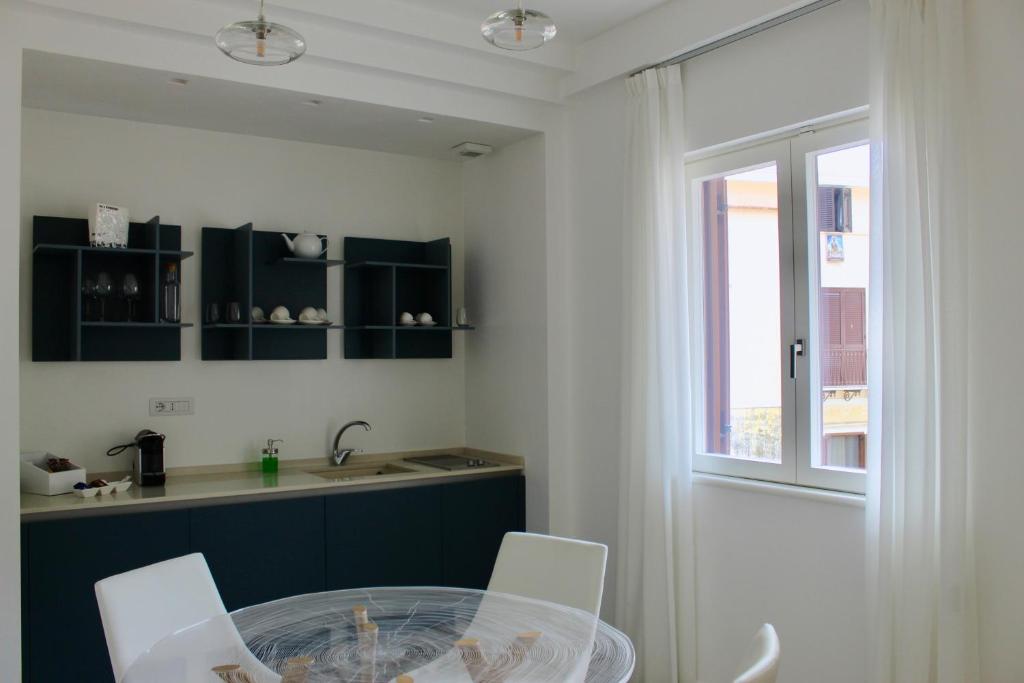 a kitchen with a glass table and white chairs at Cetara Costa d'Amalfi Residence in Cetara