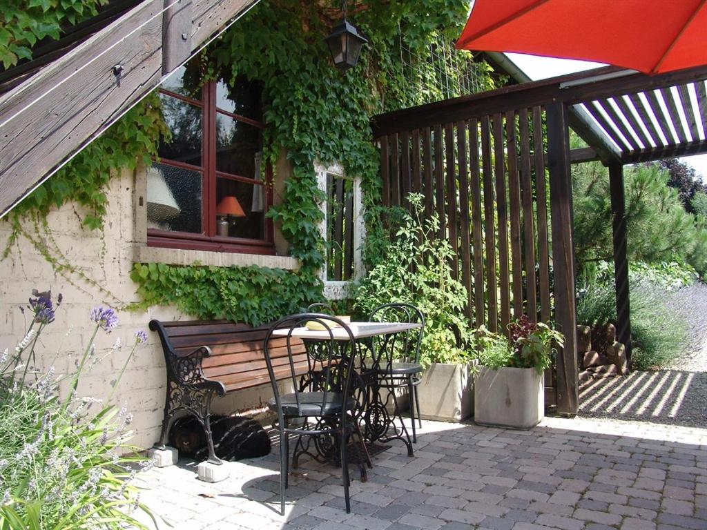 un patio con mesa, sillas y sombrilla en Les Gîtes de l'Escalier, en Brumath