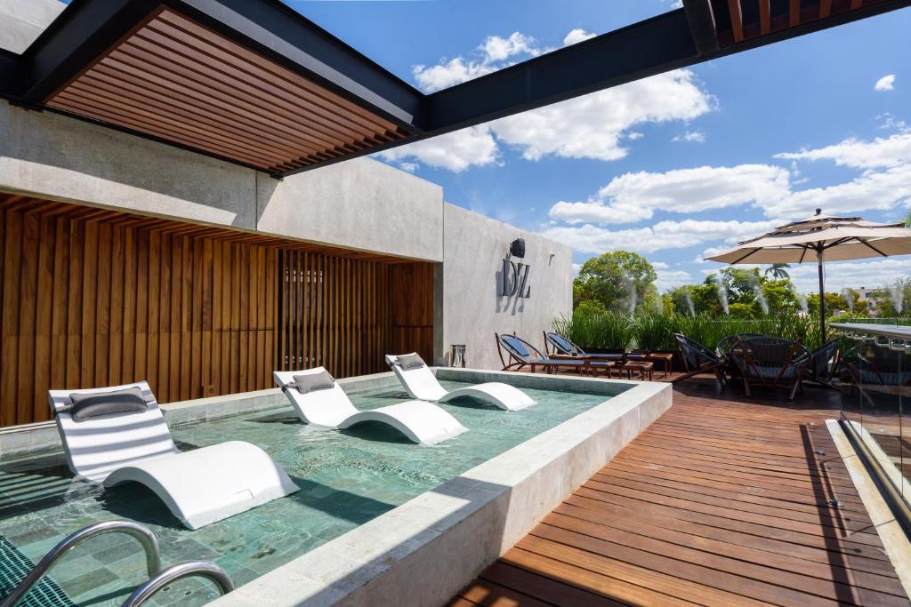 an outdoor pool with white chairs and an umbrella at Diez Diez Collection in M&eacute;rida