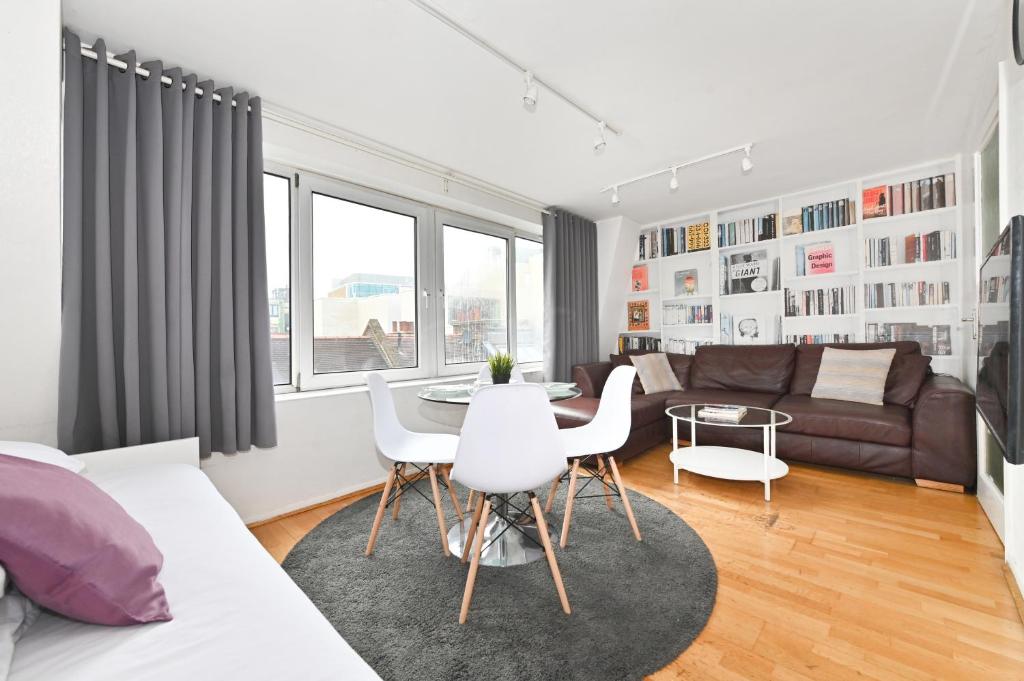 ein Wohnzimmer mit einem Sofa, einem Tisch und Stühlen in der Unterkunft Oxford Street & Carnaby - Soho Abode Apartments in London