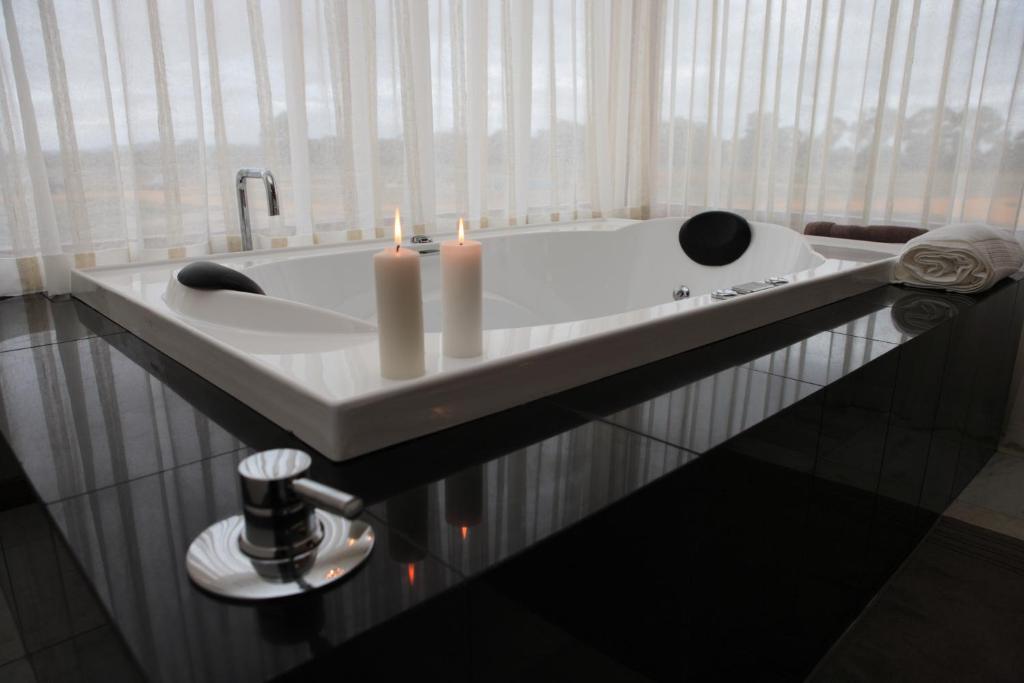 a bathroom with a bath tub with candles in it at Aurora Cottages Bush Retreat in Halls Gap