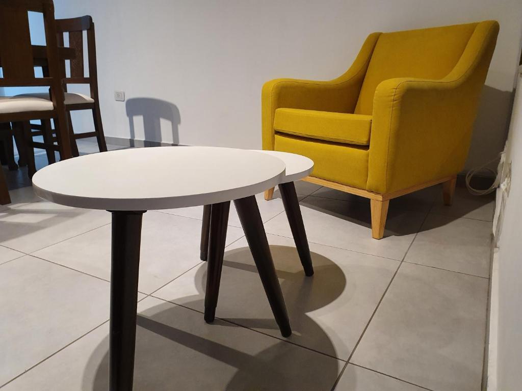 a white table and a yellow chair in a room at Apartamento Deluxe Senderos del Vino II, desayuno Opcional in Mendoza