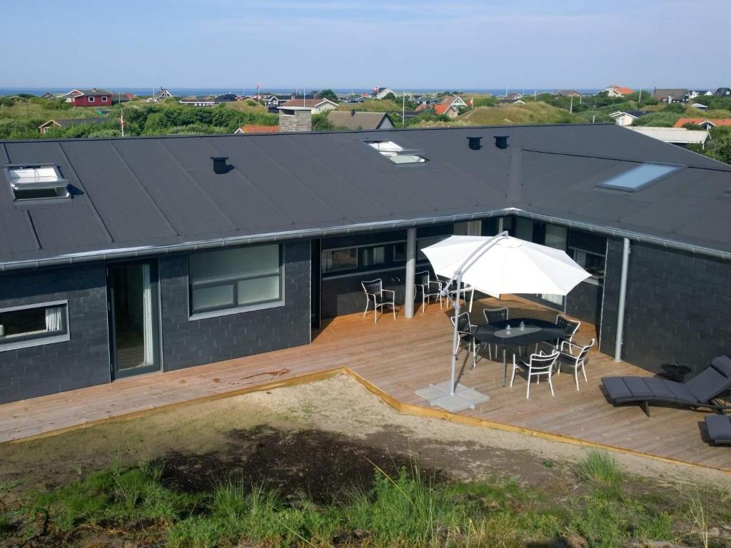 ein Haus mit einer Terrasse mit einem Tisch und einem Sonnenschirm in der Unterkunft Holiday home Fanø CLXXXIV in Fanø