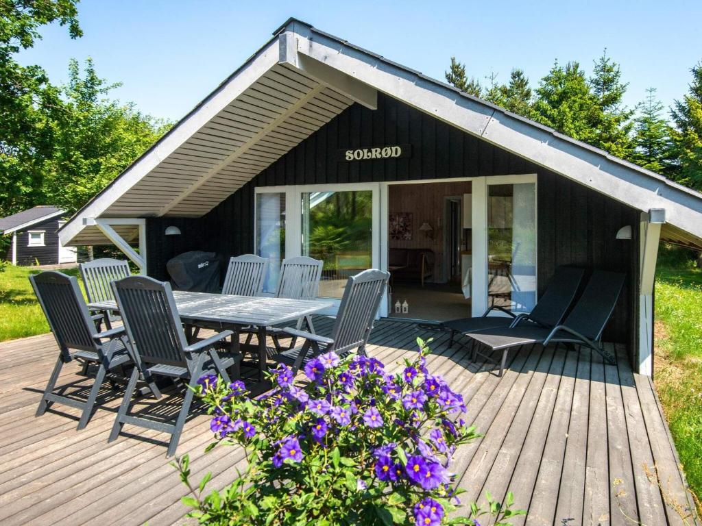 スナーヴィグにあるThree-Bedroom Holiday home in Ringkøbing 26のデッキ(テーブル、椅子、紫の花付)