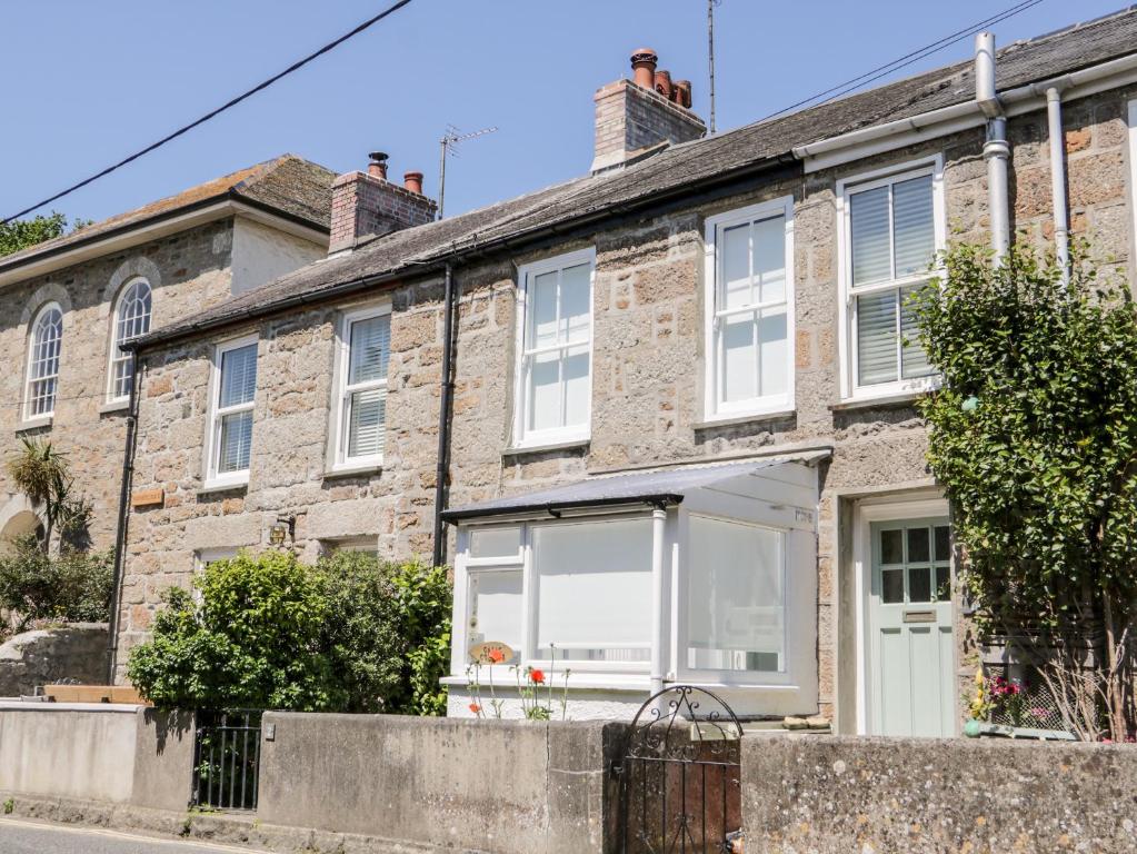 an old brick house with a white awning at Calac Cottage in Mousehole