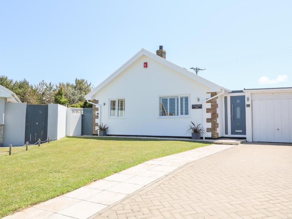 a white house with a fence and a driveway at Holywell Bay View in Newquay