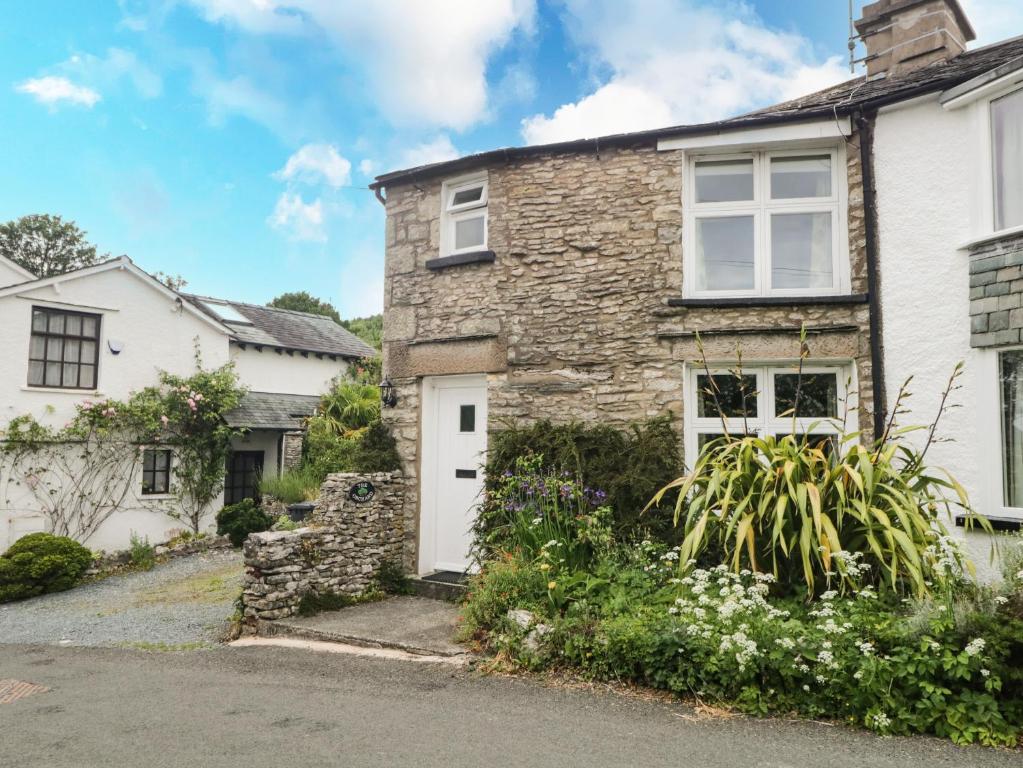 uma antiga casa de pedra com uma porta branca e flores em The Orchard em Kendal