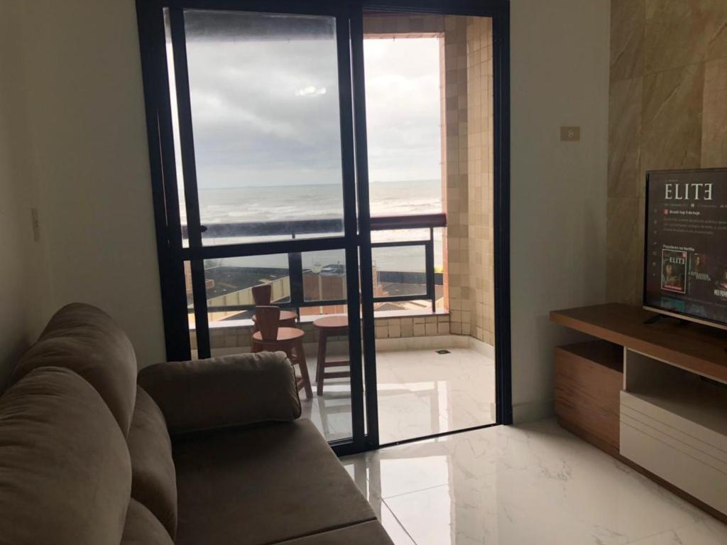 a living room with a couch and a view of the ocean at Apartamento solar vitória regia - Frente Mar in Praia Grande