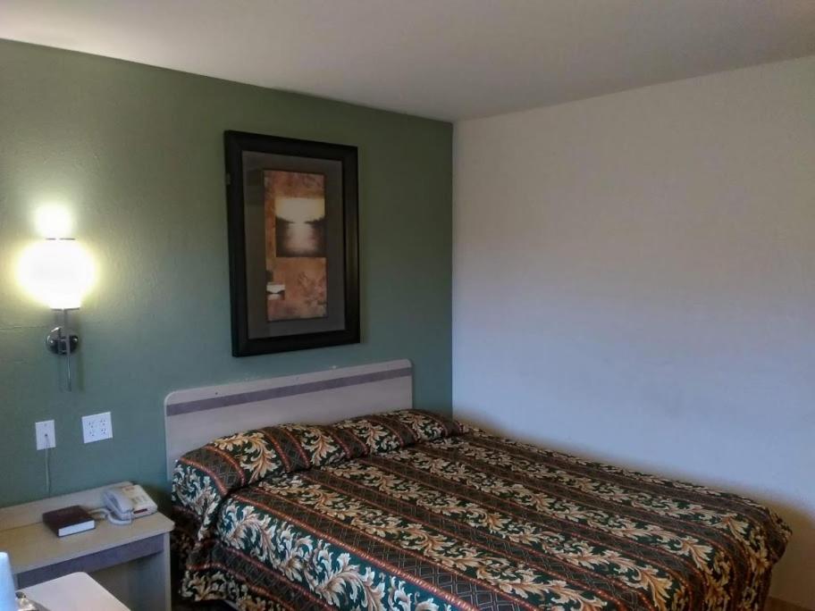 pokój hotelowy z łóżkiem i zdjęciem na ścianie w obiekcie RED CARPET INN LOUISVILLE NORTH -Jeffersonville In w mieście Jeffersonville