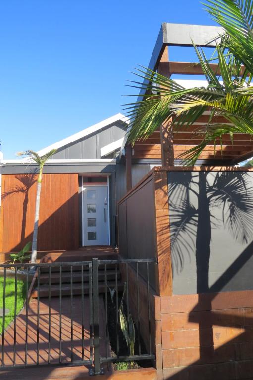 a house with a gate and a palm tree at Two Palms in Gisborne
