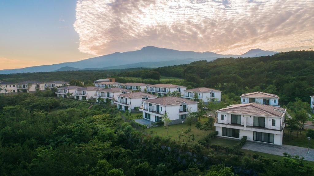 a group of houses on a hill with mountains in the background at Kylin Villa resort Jeju in Seogwipo