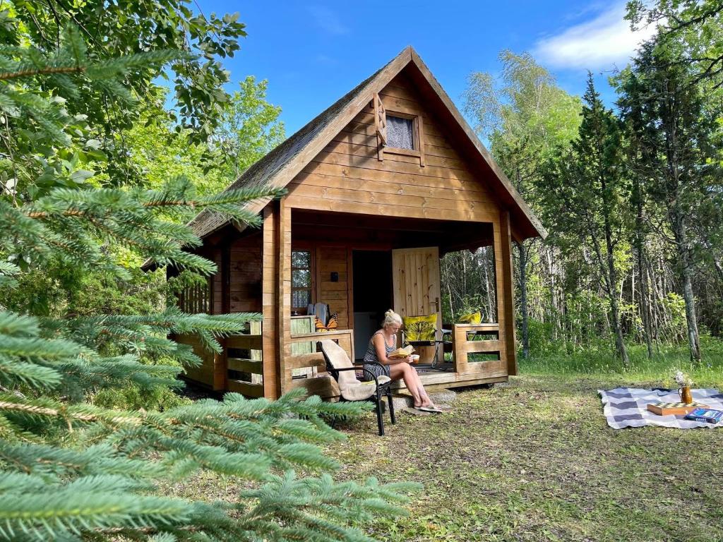 une femme assise sur une chaise devant une cabine dans l'établissement Intsu cabin ''Marju Kuut'', à Liiva