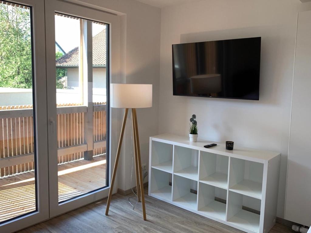 ein Wohnzimmer mit einem TV und einem Tisch mit einer Lampe in der Unterkunft Gästehaus Hirsch 93 in Straubenhardt