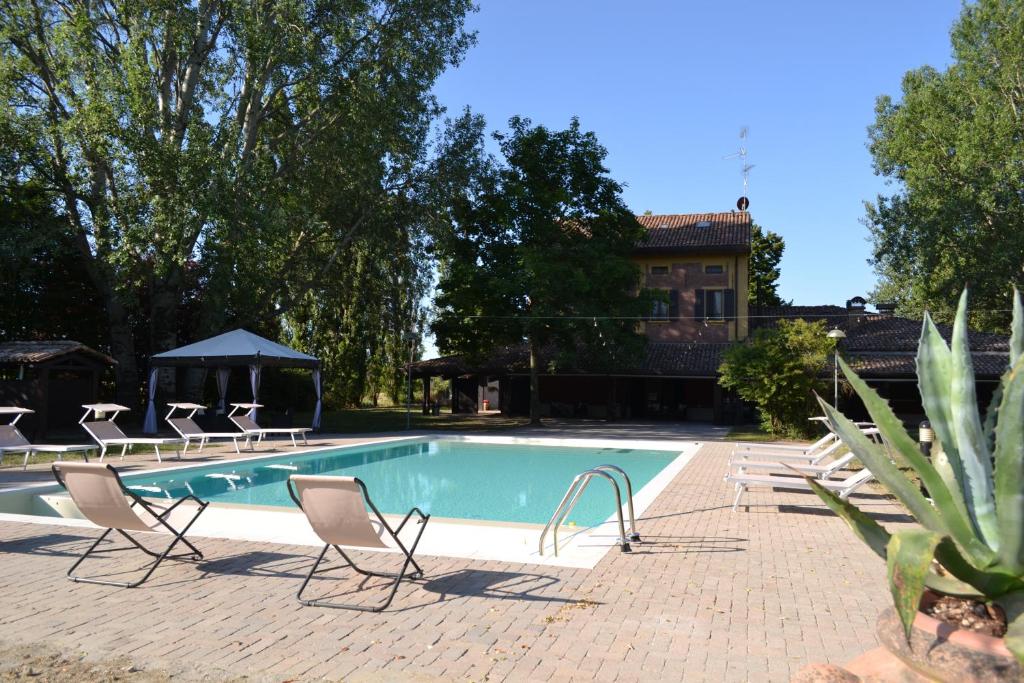 uma piscina com cadeiras e uma casa ao fundo em La Locanda nel Frutteto em Rovereto