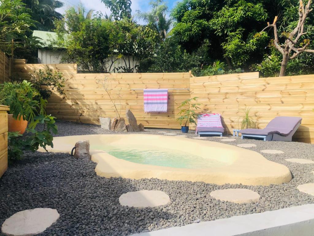 una piccola piscina in un cortile con due sedie di Le Coton Bleu 974 a Le Bois de Nèfles